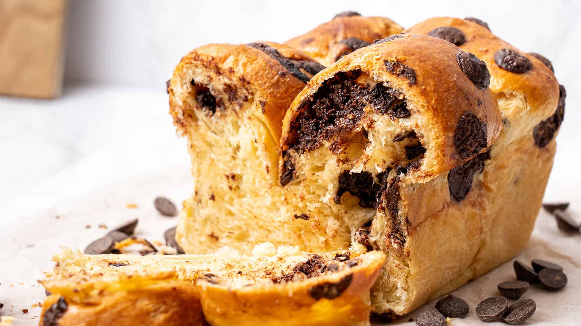 Chocolate chip brioche cut half on a baking sheet.